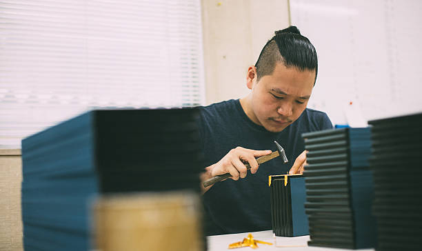 Young man creating a wooden craft box. Young man creating a wooden craft box. He is working with hammer. He is staying in the studio and there is nobody else. late modern period stock pictures, royalty-free photos & images