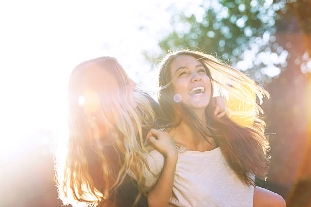 zwei teenager lachen im park - beauty in nature women beautiful human teeth stock-fotos und bilder