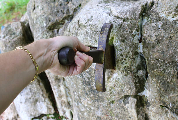 istock hand and excalibur sword in the stone 479277556