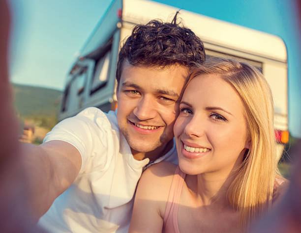 Young couple with a camper van Beautiful young couple in front of a camper van on a summer day teenager couple child blond hair stock pictures, royalty-free photos & images