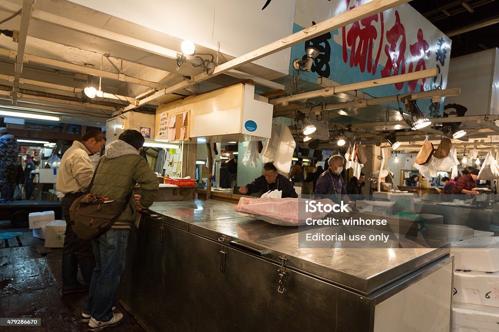 Tsukiji Fish Market in Tokyo, Japan Tokyo, Japan - December 22, 2014 : People at the Tsukiji Fish Market, it is the biggest wholesale fish and seafood market in the world. The market is located in central of Tokyo, and is a major attraction for foreign visitors.  2015 Stock Photo