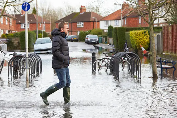 Photo of Man Walking Along Flooded Urban Street