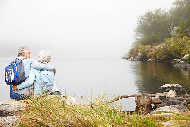 istock Senior couple sit embracing by a lake, back view 479287924