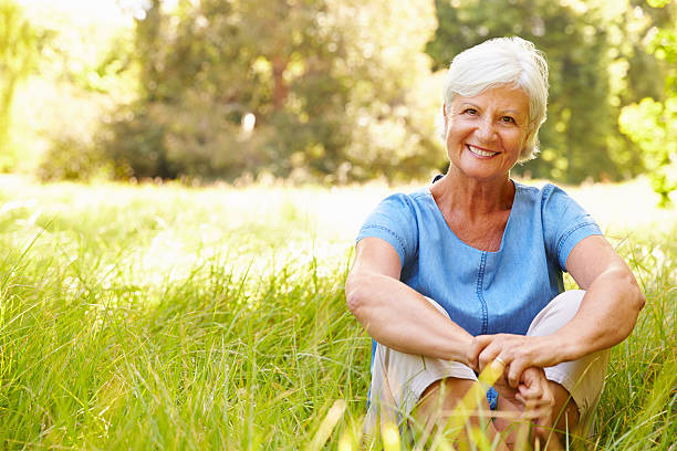 istock Senior woman sitting on grass relaxing, smiling to camera 479288044