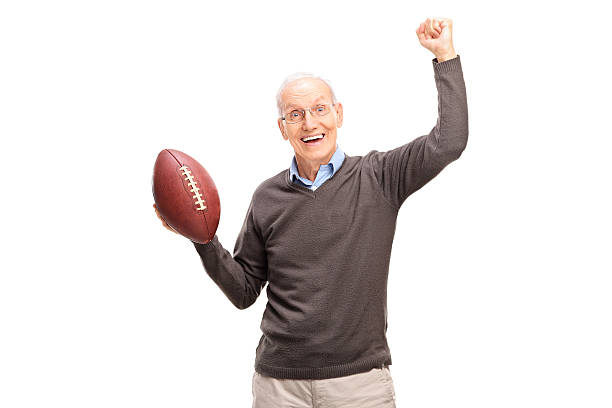 Joyful senior man holding an American football Studio shot of a joyful senior man holding an American football and gesturing happiness isolated on white background old football stock pictures, royalty-free photos & images