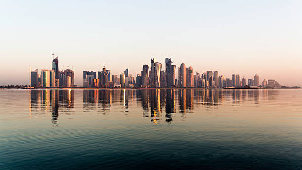 Doha City Qatar at sunrise Early morning sunrise golden light hits the city of Doha in Qatar. A wide angle view from across the bay including a typical dhow. dhow photos stock pictures, royalty-free photos & images