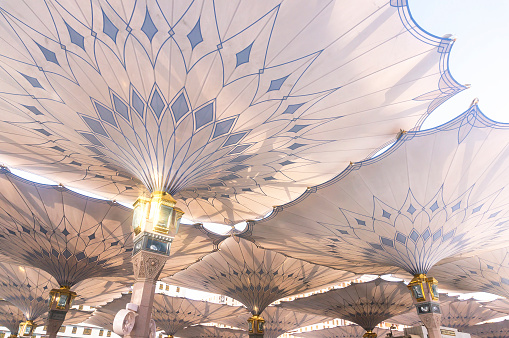 Medina, Saudi Arabia - March 8, 2015: Underneath giant umbrellas at Nabawi Mosque compound. Nabawi mosque is the second holiest mosque in Islam.