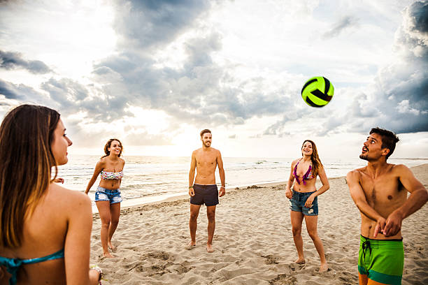 grupo de amigos a jogar vólei na praia - volleying sport summer men imagens e fotografias de stock