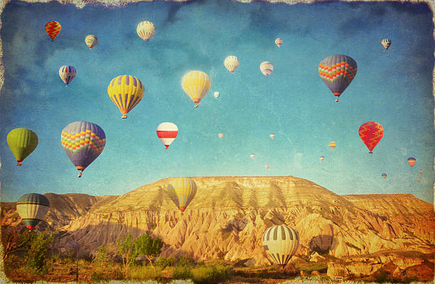 Grunge image of colorful hot air balloons against blue sky Old landscape postcard of colorful hot air balloons against blue sky cappadocia balloon stock illustrations