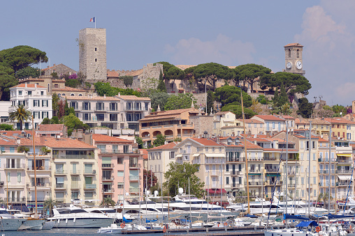 Harbor and town of Cannes with Castle of Suquet and church Notre-Dame-d'Espérance. Cannes is a city located on the French Riviera. It is a commune of France located in the Alpes-Maritimes department