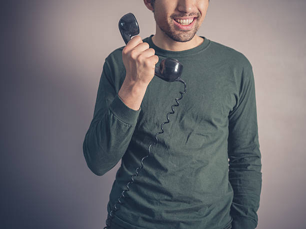 heureux jeune homme avec téléphone vintage - retro revival telephone human hand toned image photos et images de collection