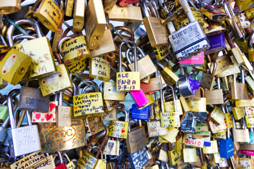Paris, France - July 7, 2013: Locks inscribed with the names of lovers adorning a bridge in Paris.