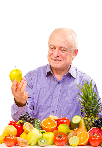 istock senior man holding a yellow apple 479307855