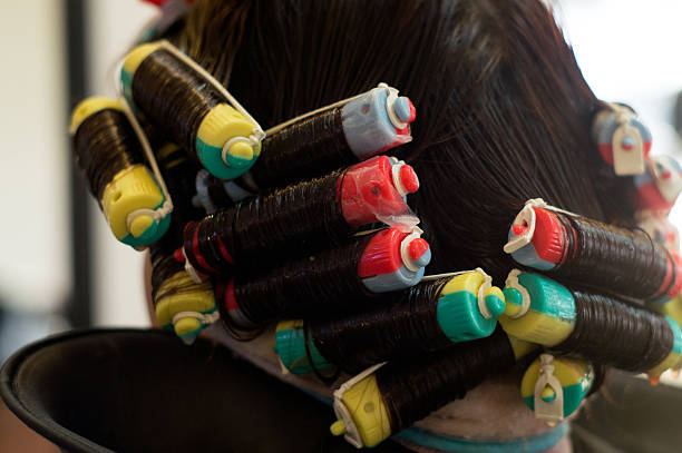 perm rolling the hair onto fine rollers or curlers stock photo