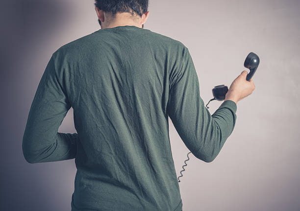 вид сзади человека, используя телефон с диском - retro revival telephone human hand toned image стоковые фото и изображения