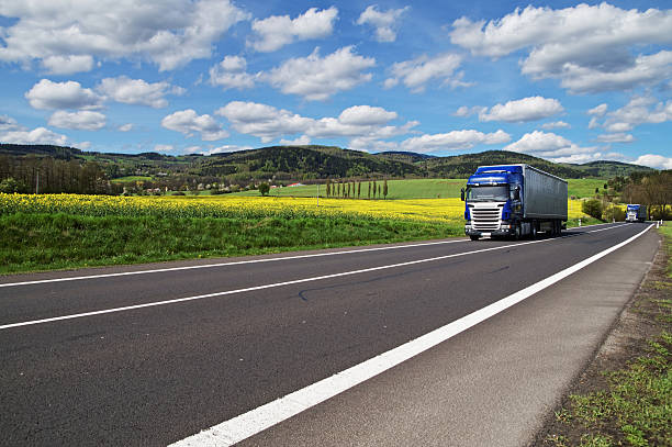 istock Trucks driving on the road between yellow flowering rapeseed 479311420
