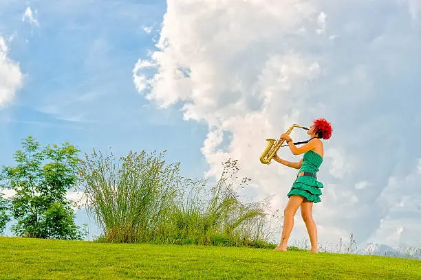 Photo of Young saxophonist (woman with the red hair) playing saxophone in