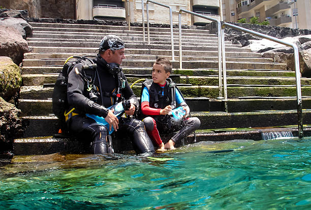 His first dive First dive for a child, attentively following the instructions of his father scuba diving family stock pictures, royalty-free photos & images