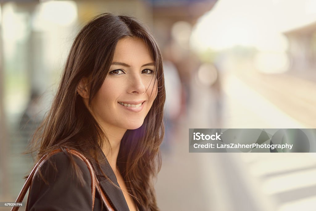 Smiling brunette woman Smiling brunette woman standing in a train station in the morning, commuting to work in an eco-friendly manner Train - Vehicle Stock Photo