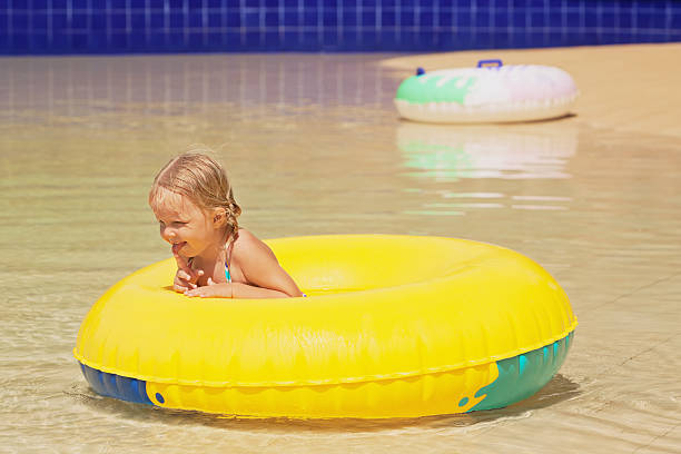 drôle portrait d'une joyeuse petite fille dans le parc aquatique de la piscine - water sport family inner tube sport photos et images de collection