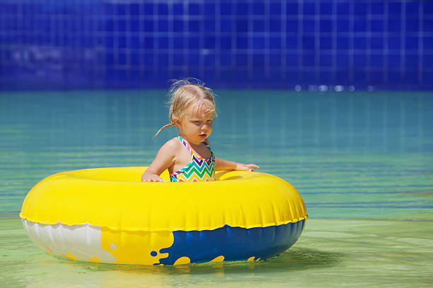 drôle portrait d'une joyeuse petite fille dans le parc aquatique de la piscine - water sport family inner tube sport photos et images de collection