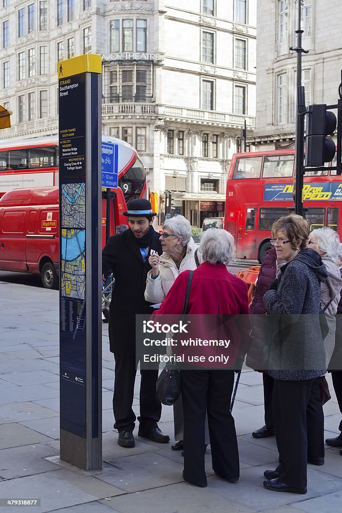 ‘Northbank Ambassador’ in Strand, London London, England - March 5, 2014: A ‘Northbank Ambassador’ helping a group of tourists in Strand, London. The Northbank Ambassadors are multi-lingual and assist tourists and local businesses as well as watching out for street issues such as missed rubbish collections, antisocial behaviour and graffiti. Also known as “The Welcome People”, they work for the Northbank Business Improvement District. Adult Stock Photo