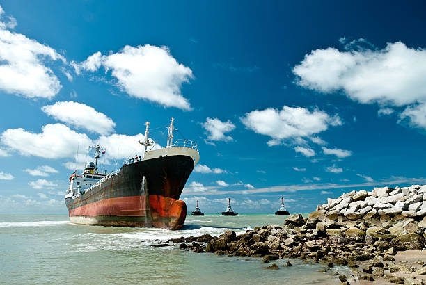 Cargo ship run aground on rocky shore Cargo ship run aground on rocky shore waiting for rescue. stranded stock pictures, royalty-free photos & images