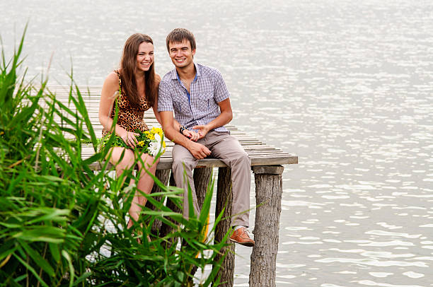 Young girl and the young man on the dock by the river stock photo