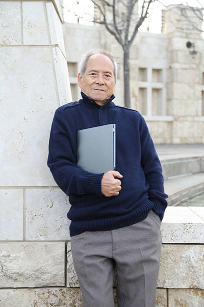 istock University professor holding laptop 479328945