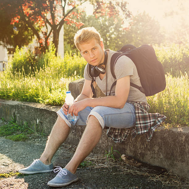 Young hipster hombre con mochila en el parque y auriculares - foto de stock