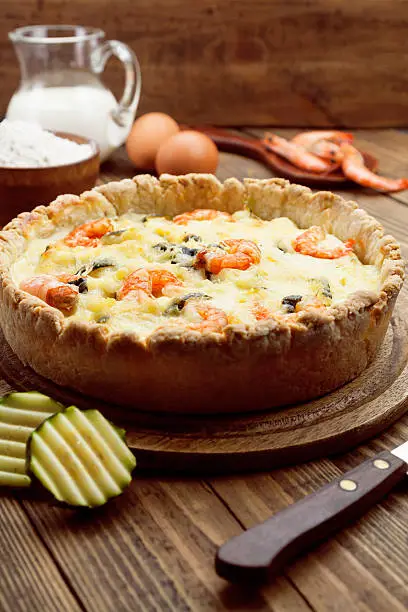 Quiche with shrimp and zucchini on a wooden tableQuiche with shrimp and zucchini on a wooden table