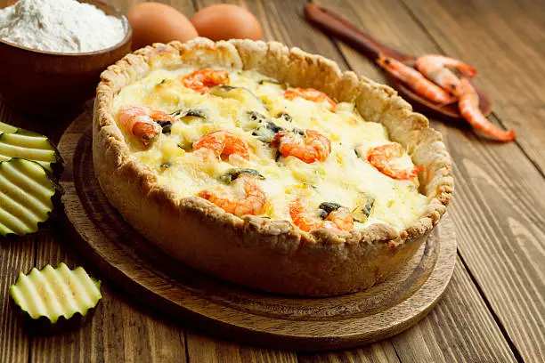 Quiche with shrimp and zucchini on a wooden tableQuiche with shrimp and zucchini on a wooden table