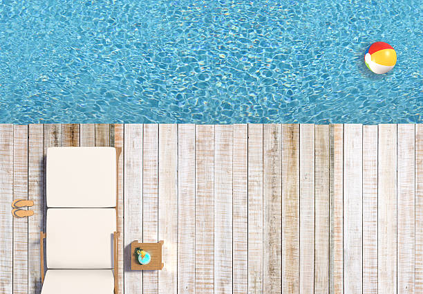 This is a bird view, wooden decking on the blue water, summer scene showing holiday like setup, decking, water, chair, cocktail, ball....
