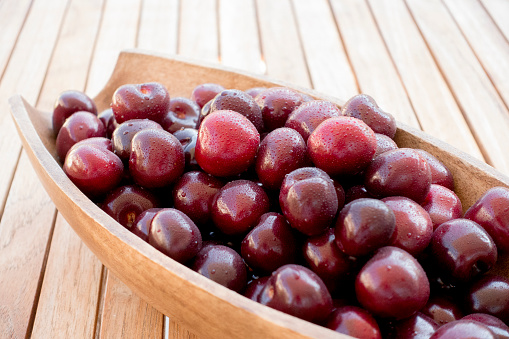 Bowl of sweet cherries on wooden table