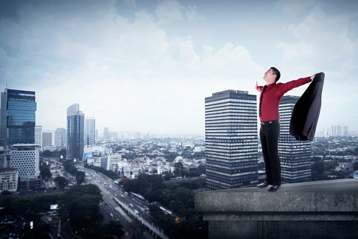 Happy businessman standing on the rooftop of a skyscraper over a cityscape