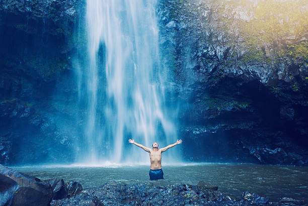 istock Man in pool at the base of large waterfall 479357796