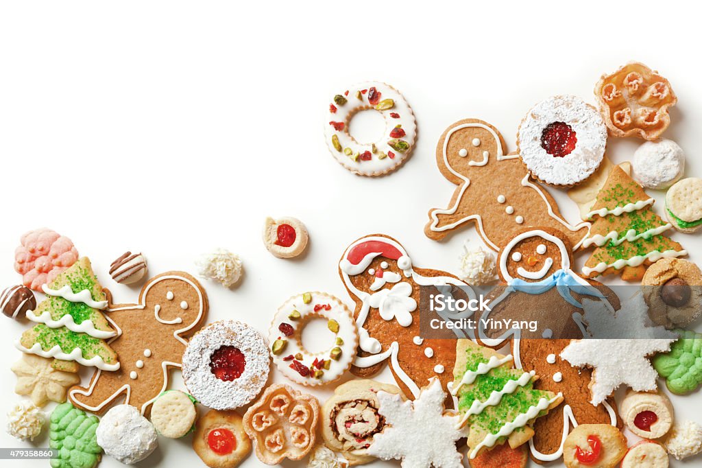 Christmas Cookies Top Corner Frame Border on White Background a collection of Christmas cookies, including gingerbread man, Christmas trees and snowman cookie, chocolate, frosting, dried fruit topping, decorated with white and red icing for holiday treat desserts. Isolated on white background. Photographed as a decorative frame corner border with copy space available for custom text and copy. Christmas Stock Photo