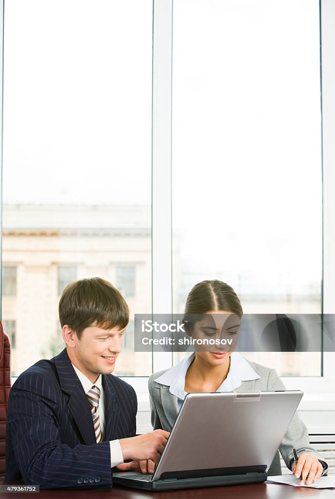 In the office Vertical image of two working people on background of window in office 2015 Stock Photo