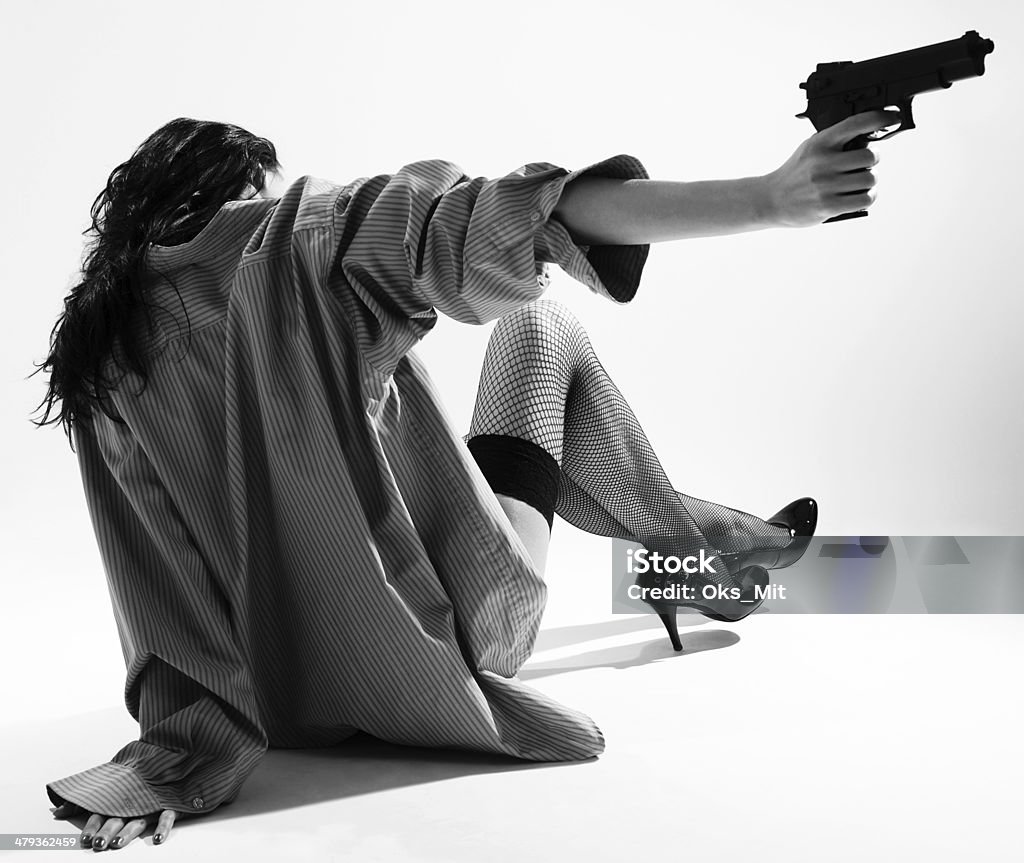 Undressed fille se trouve à l'arrière et vise à pistolet - Photo de Adulte libre de droits