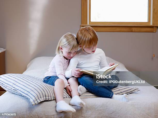 Irmãs Ler Um Livro Na Cama - Fotografias de stock e mais imagens de Almofada - Roupa de Cama - Almofada - Roupa de Cama, Cabelo Curto - Comprimento de Cabelo, Cabelo Louro