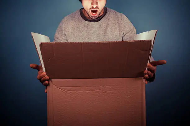 Photo of Surprised young man opening exciting box
