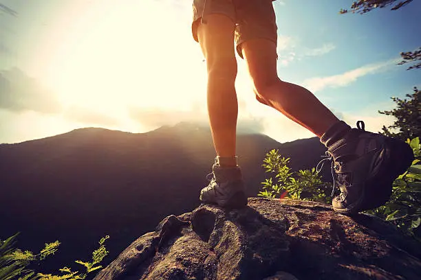 woman hiker legs stand on mountain peak rock