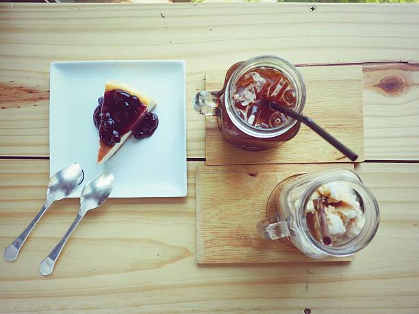 Ice coffee and blueberies cheese cake on wood table, vintage.