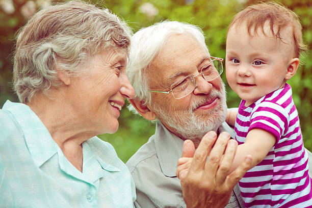 Grandparents with their granddaughter outdoors happy and together.