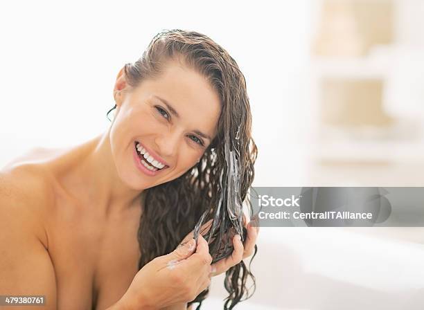 Smiling Young Woman Applying Hair Conditioner Stock Photo - Download Image Now - Shampoo, Hair Care, Human Hair