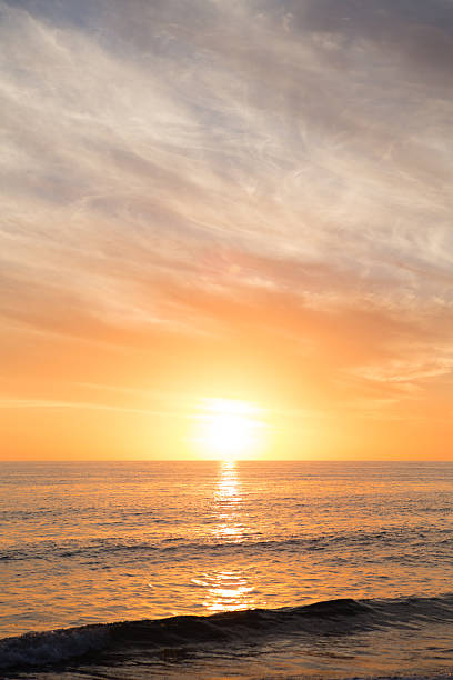 Color stock photo of the sun setting on the horizon over the ocean on a beautiful beach on Sanibel Island, Florida.