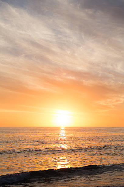 Sun Setting on Horizon over Ocean with Waves at Beach stock photo