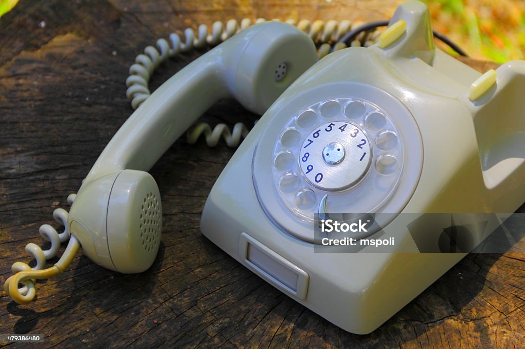 Vintage telephone Retro beige rotary phone over wooden surface with sunset lights         1970-1979 Stock Photo