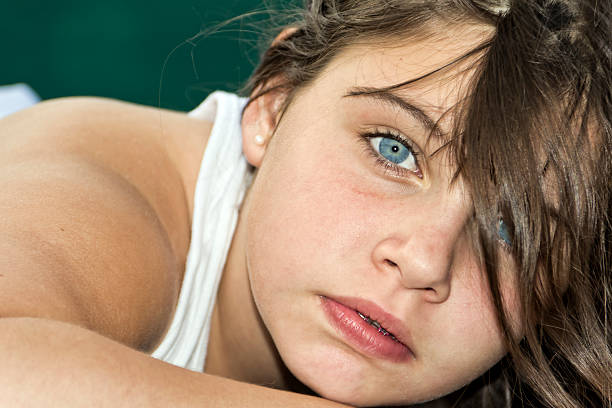 This image captures a close-up portrait of a young woman, featuring her captivating blue eye makeup and a calm expression. She wears hoop earrings and has her hair neatly styled back.