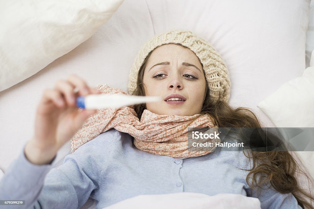 Sick woman Sick woman with thermometer is lying in bed. She has cold, flu and high fever. Adult Stock Photo